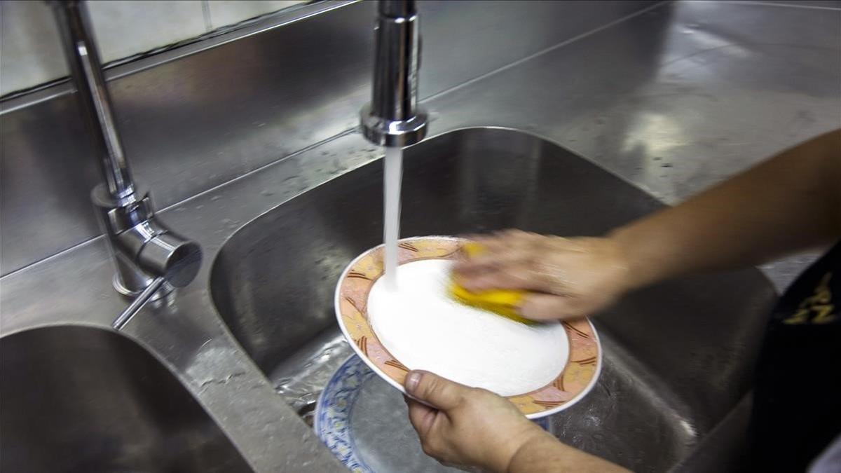 Una persona lava platos en un bar-restaurante de Barcelona.