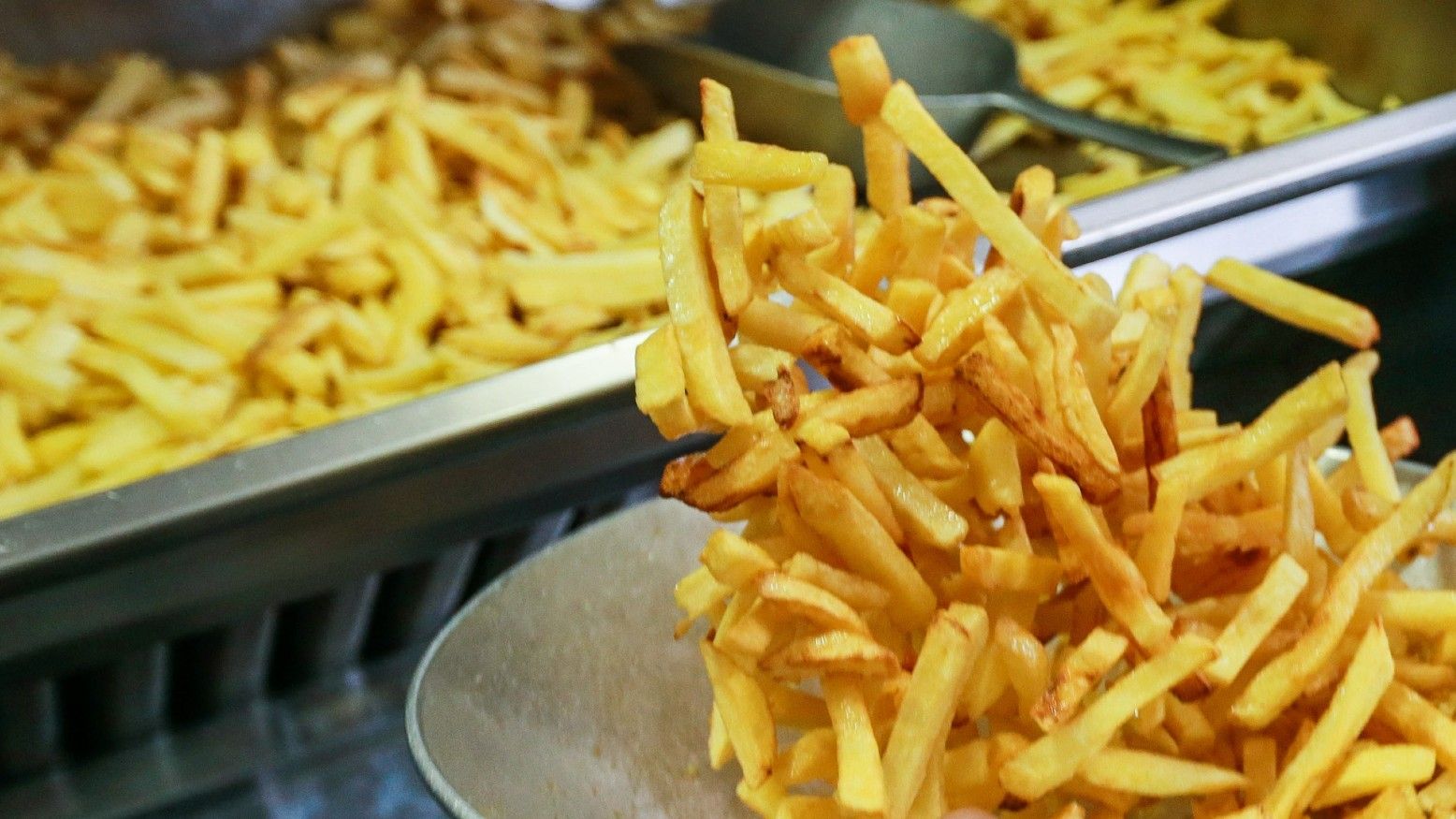 Un hombre remueve un recipiente lleno de patatas fritas belgas, comúnmente conocidas como ''Frites'', en Bruselas