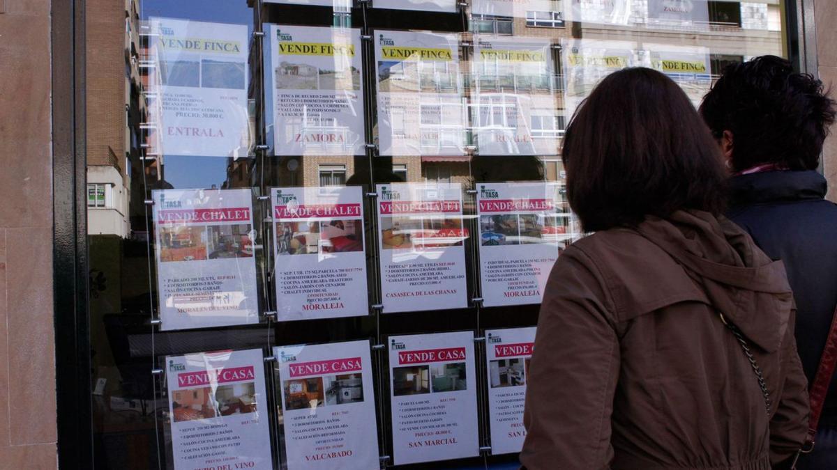 Dos zamoranas contemplan viviendas en venta en una inmobiliaria.
