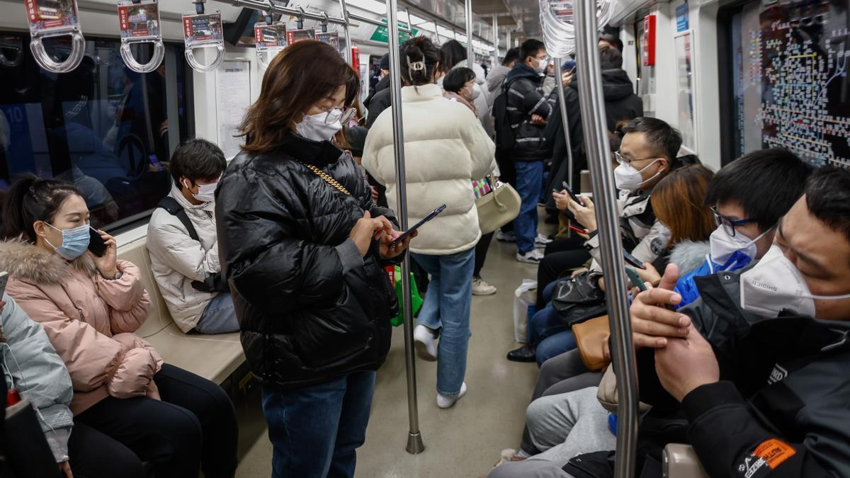 Personas usan máscaras faciales dentro de un tren en Beijing.Los científicos han advertido a China que el país enfrentará múltiples oleadas de infecciones por COVID-19 .