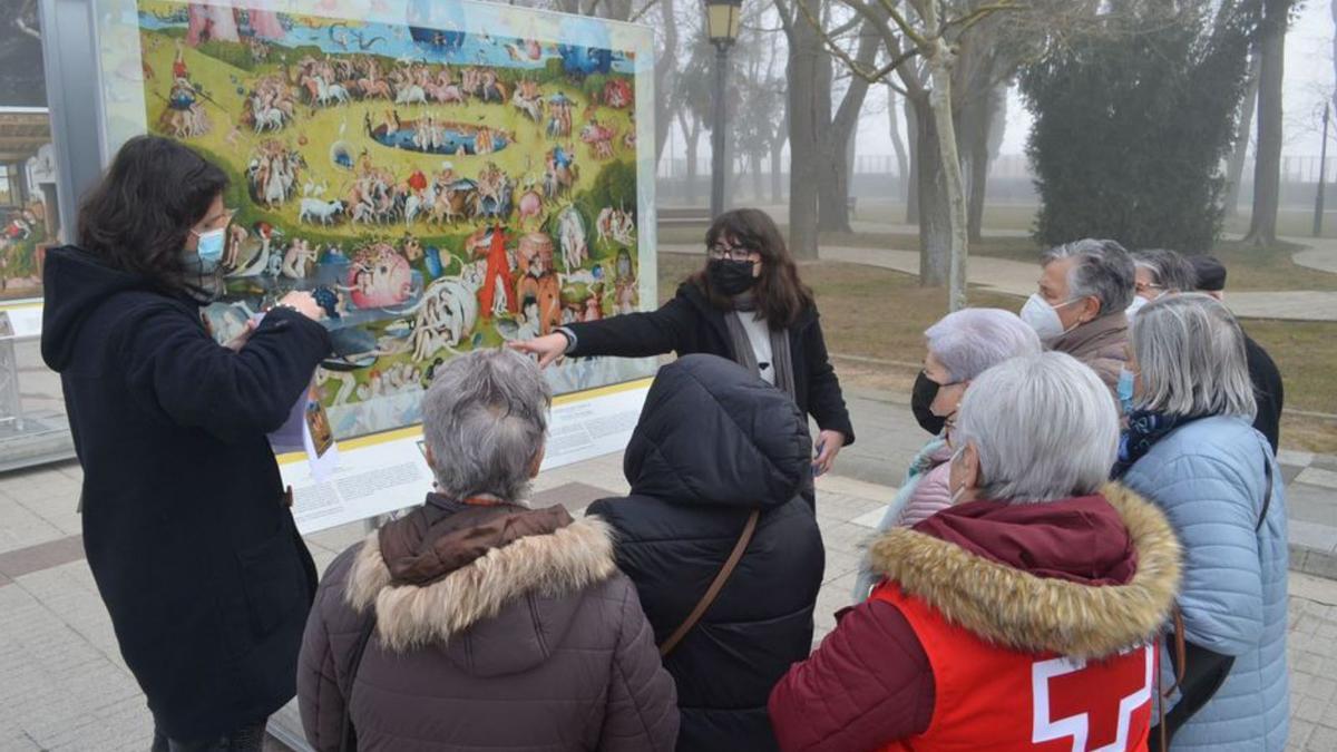 Dos jóvenes explican la simbología de “El Jardín de las delicias”, en la exposición &quot;El Prado en las calles&quot;. | E. P.