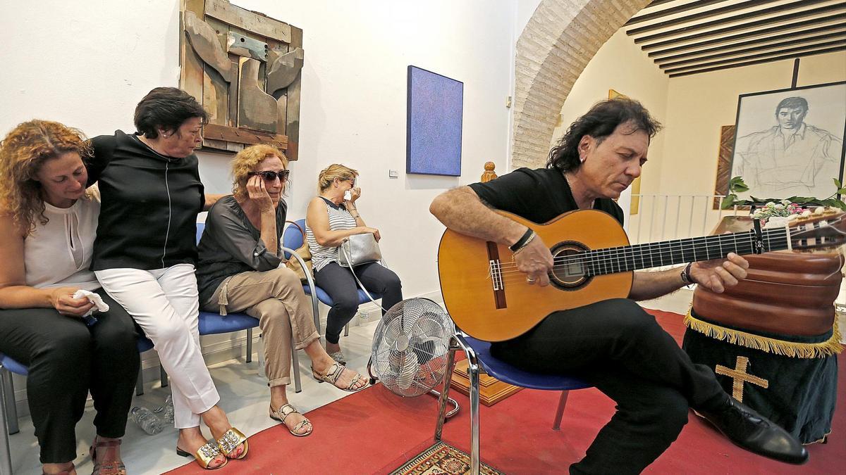 El guitarrista Antonio Carrión (d), junto a Encarnación Gil (3i), viuda del cantaor flamenco José Menese, fallecido este viernes a los 74 años, rinde un homenaje en la capilla ardiente intalada en el Museo de Arte Contemporáneo José María Moreno Galván de La Puebla de Cazalla. EFE/Jose Manuel Vidal