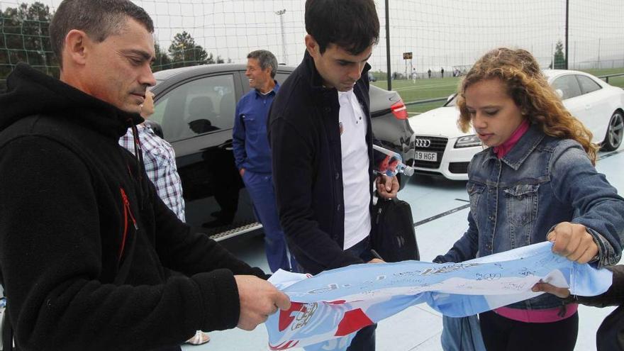 El capitán celeste, Borja Oubiña, firma una bandera con los colores del Celta a una joven aficionada al término del entrenamiento celebrado ayer a puerta cerrada en A Madroa. // Jorge Santomé