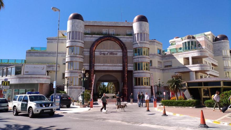 Un vecino pasea tranquilamente a dos perros por delante del edificio Rey D´Albion, conocido como el Palacio sirio, en presencia de efectivos de la Guardia Civil.