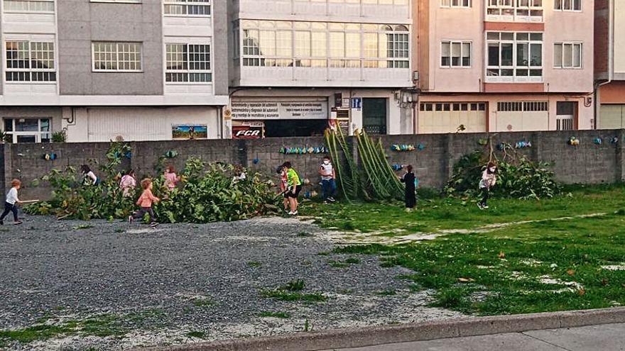 Niños junto a restos de poda en el parque de Juan Salgueiro.