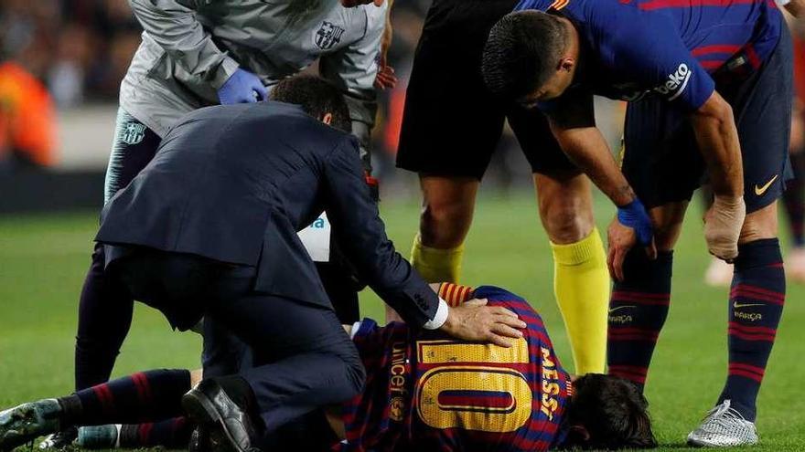 Los servicios sanitarios del Barcelona atienden a Leon Messi, dolorido en el césped, con Luis Suárez a su lado