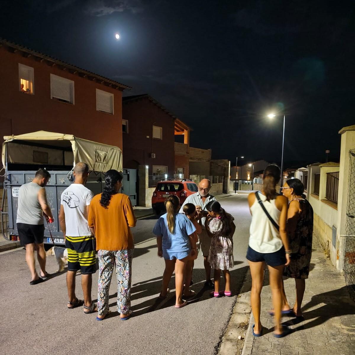 Los vecinos se reúnen en la calle durante el primer paseo nocturno a la luz de las farolas.