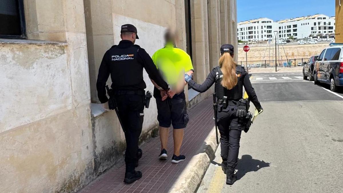 Agentes de la Policía Nacional llevan detenido a uno de los tres presuntos agresores de un joven en Ciutadella