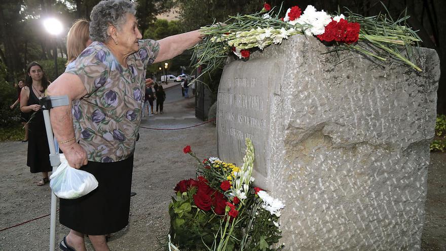 Una mujer deposita flores en el monolito dedicado a Federico García Lorca en la localidad de Alfacar, cerca del lugar donde fue asesinado hace ahora 80 años.