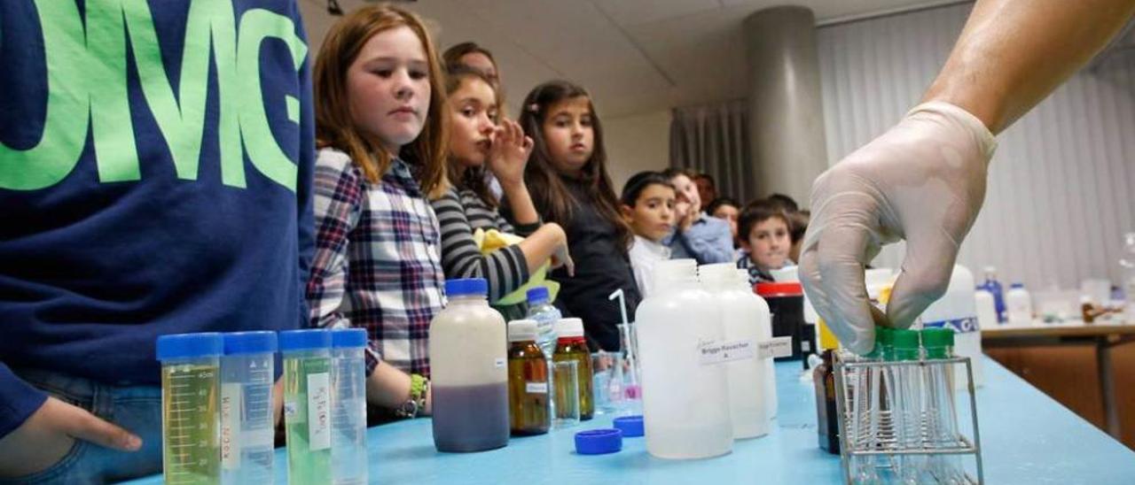 Padres e hijos contemplan al investigador de la Universidad de Oviedo durante un experimento con imanes.