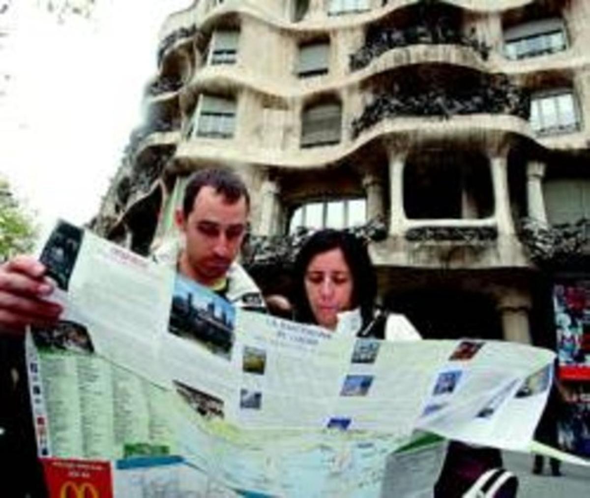 Dos turistes consulten un plànol de Barcelona davant de la Pedrera, ahir.