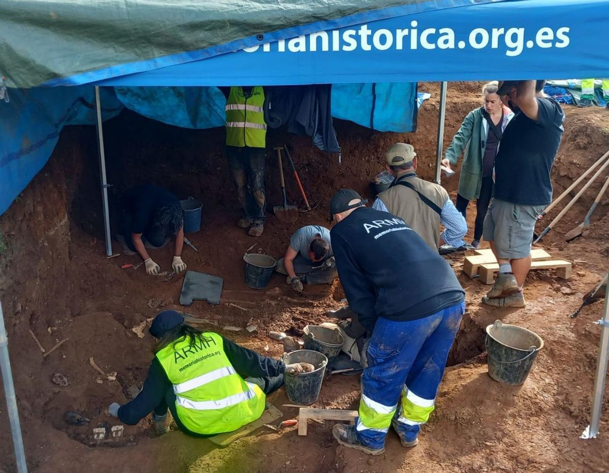 El equipo de arqueólogos limpiando los restos óseos de dos cuerpos hallados estes jueves en Bértoa /armh