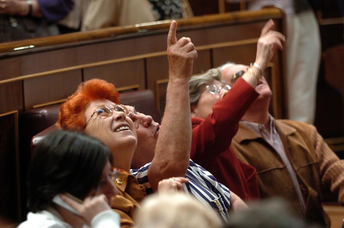 Varias personas observan los agujeros en el techo del hemiciclo del Congreso provocados por disparos el 23-F, durante las XI edición de las Jornadas de Puertas Abiertas de la Cámara Baja.