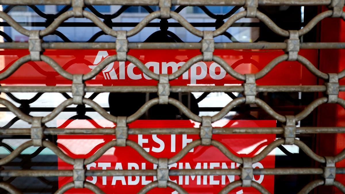 Entrada a un supermercado Alcampo de Zaragoza con la persiana bajada.