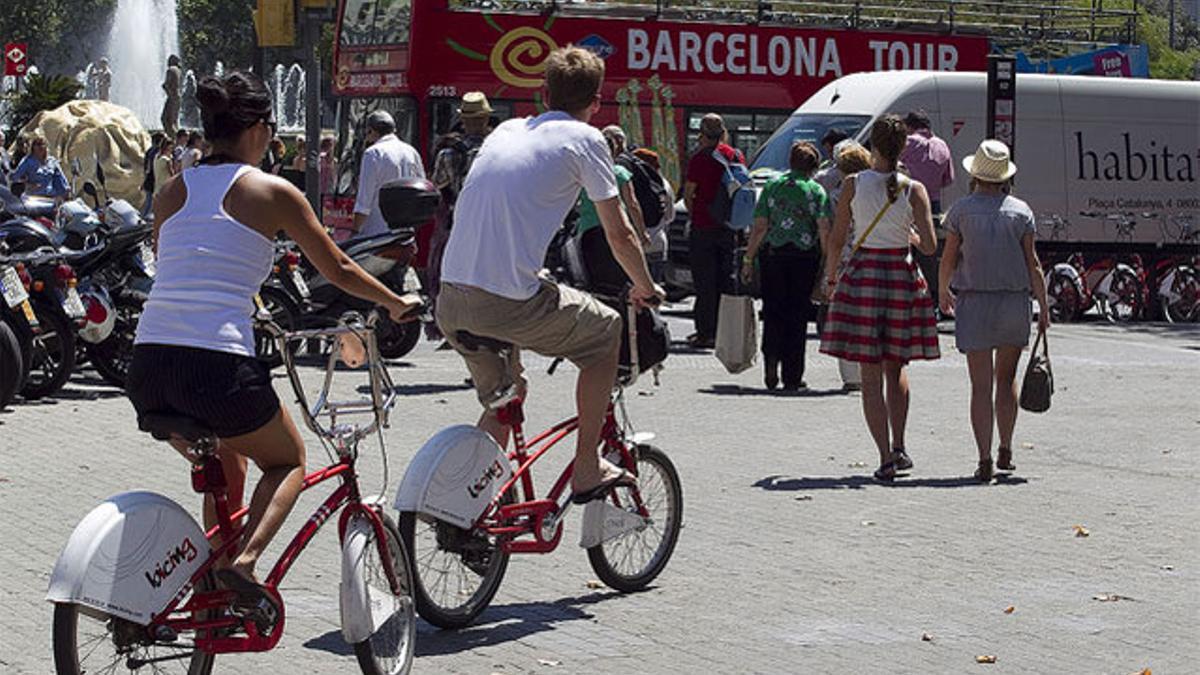 Dos ciclistas circulan por una de las aceras de la plaza de Catalunya, llena de peatones, ayer.