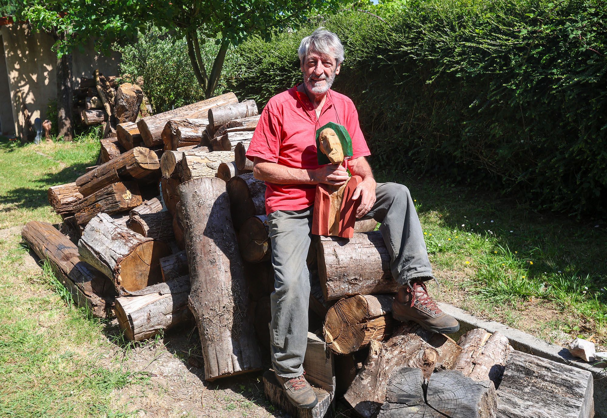 El artista con una de sus piezas sobre los troncos apilados que convertirá en esculturas.