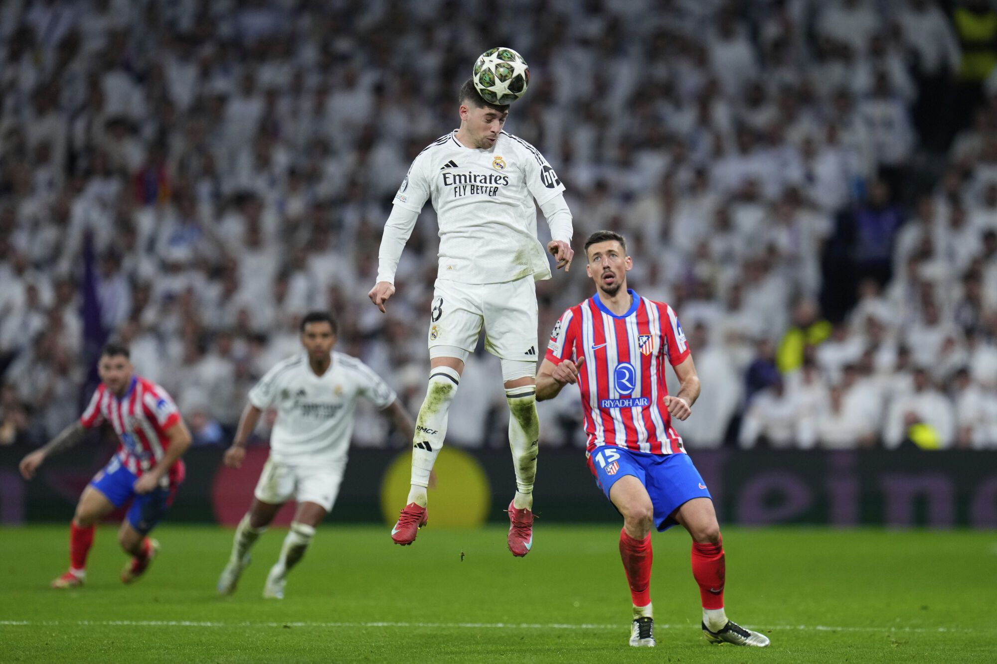 Real Madrid's Federico Valverde heads the ball past Atletico Madrid's Clement Lenglet during the Champions League round of 16 first leg soccer match between Real Madrid and Atletico Madrid at the Bernebeu stadium in Madrid, Spain, Tuesday, March 4, 2025. (AP Photo/Manu Fernandez)