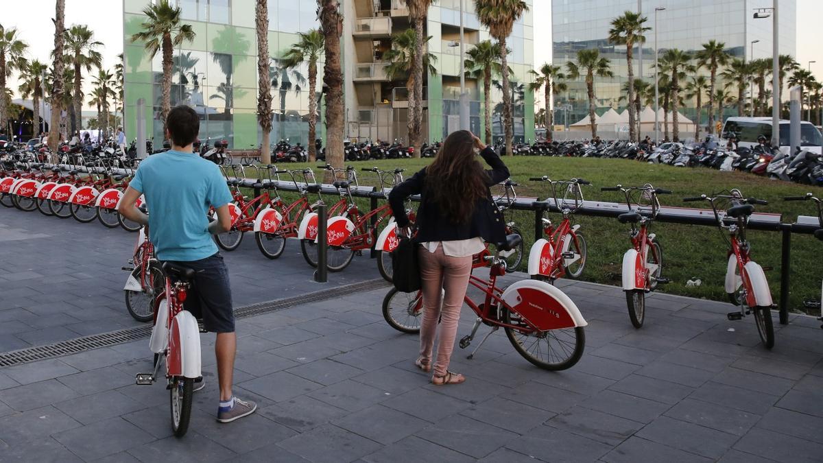Dos usuarios del Bicing esperan a que se libere un hueco para poder dejar su bici en un anclaje de la Barceloneta.