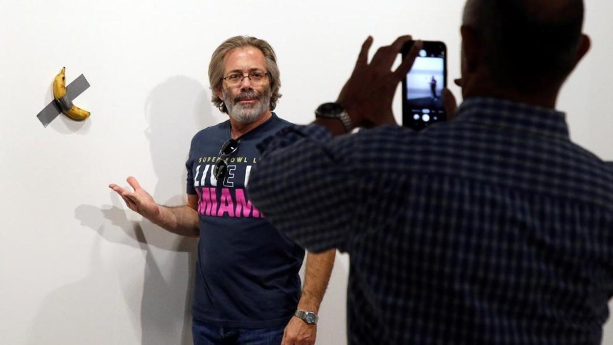 Un hombre se retrata junto a la obra del artista italiano Maurizio Cattelan