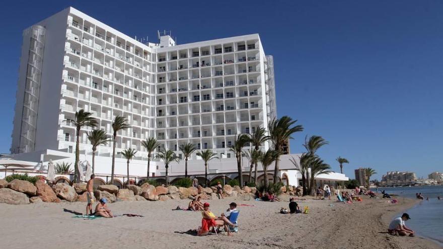 Los clientes de un hotel toman el sol en la arena junto a la orilla del Mar Menor.