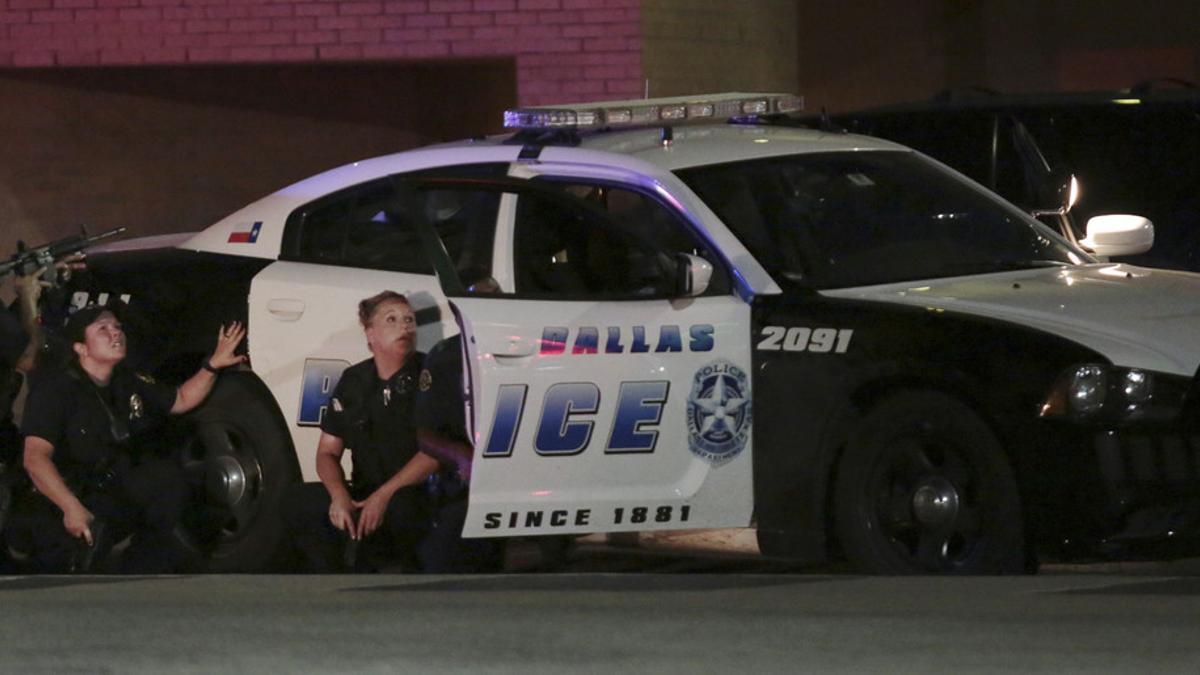 Varios policías, parapetados tras un coche patrulla, durante el tiroteo en Dallas.