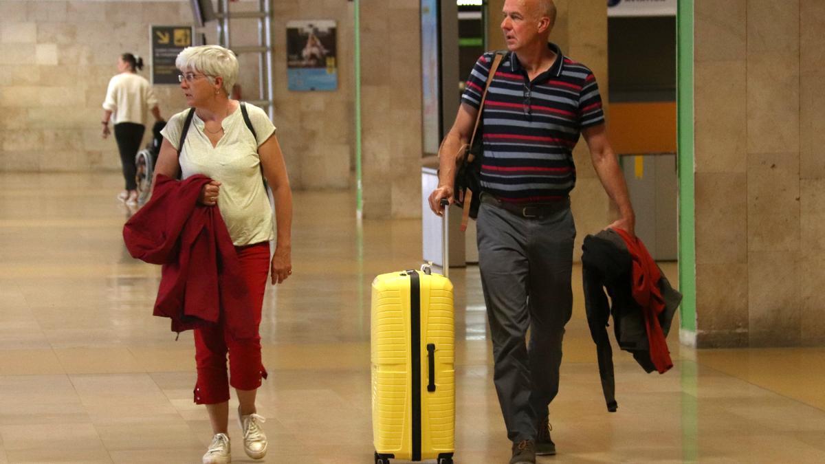 Dos passatgers de l'aeroport de Girona passegen per la terminal amb l'equipatge