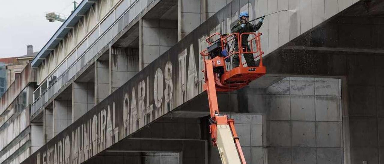 Operarios, ayer, limpiando la fachada con el letrero del estadio ya retirado.