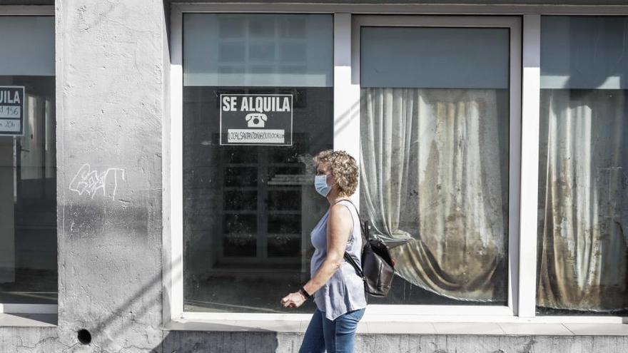 Una vecina de Sant Antoni pasea delante de un local comercial que se alquila.