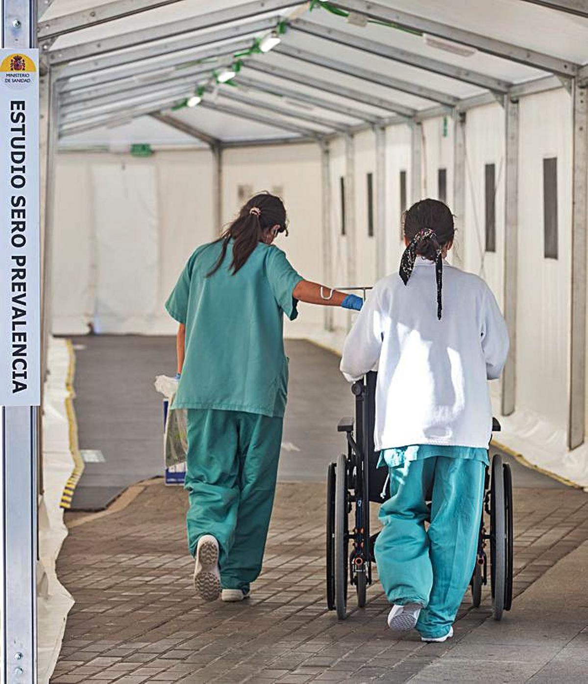 Personal de Enfermería accede al hospital de campaña. A la derecha, una enfermera hace una PCR. | RAFA ARJONES
