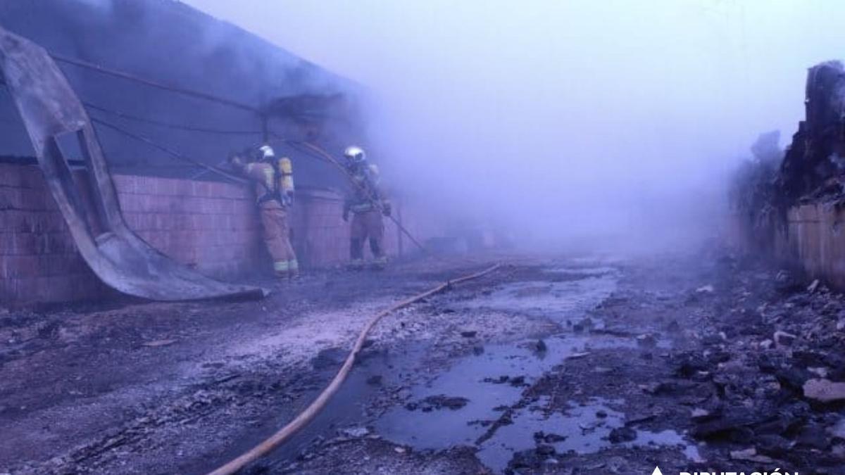 Bomberos de la Diputación Provincial de Zaragoza trabajando en la extinción del fuego en las naves porcinas de Tasute, este domingo por la mañana.