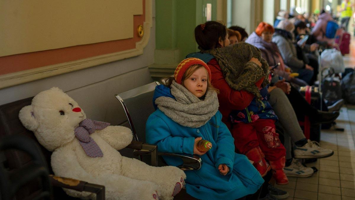 Una niña procedente de Ucrania espera, junto a su oso de peluche, un tren en la estación de tren de Przemysl, en Polonia, cerca de la frontera con Ucrania.