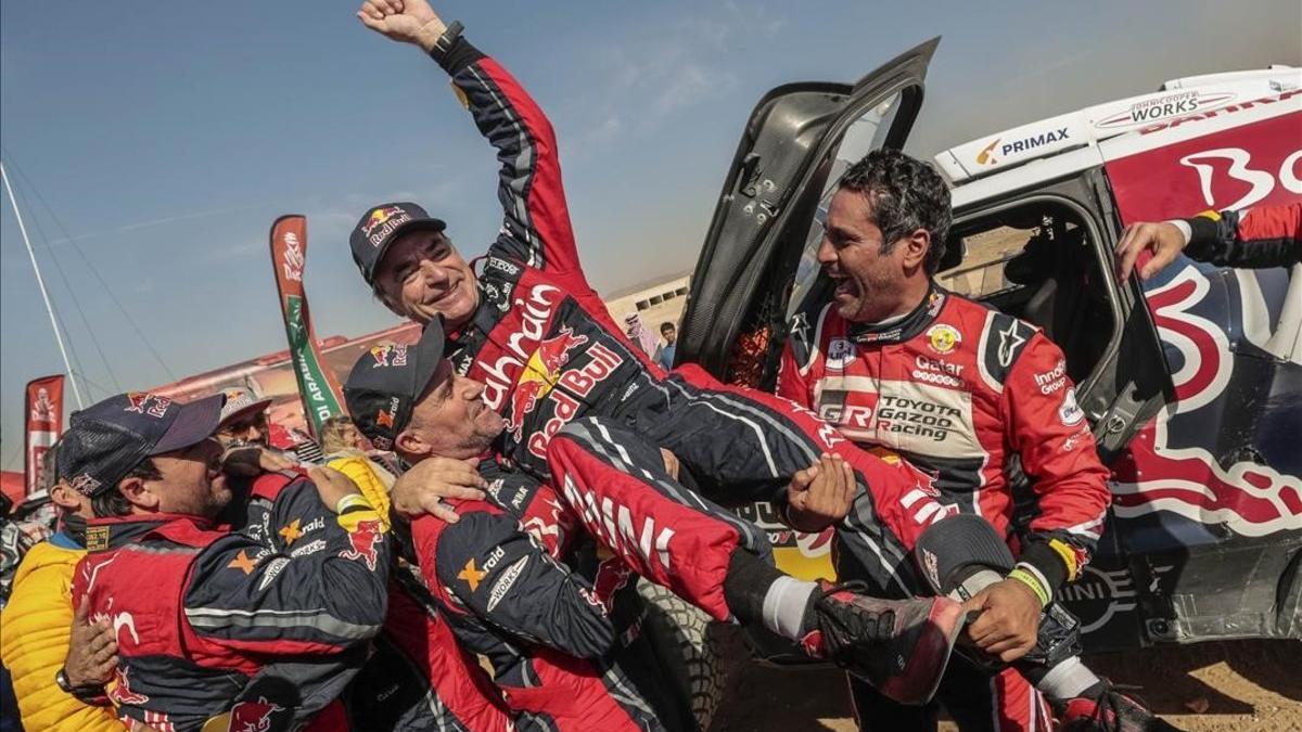 Stéphane Peterhanse 'Mister Dakar' y Nasser Al-Attiyah levantan a un triunfador Carlos Sainz, hoy, en Arabia Saudí.