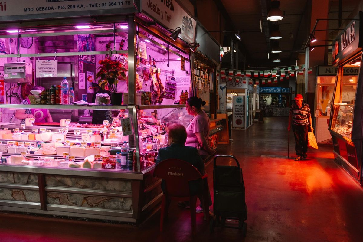 Una anciana espera sentada mientras su hija hace la compra en el Mercado de la Cebada.