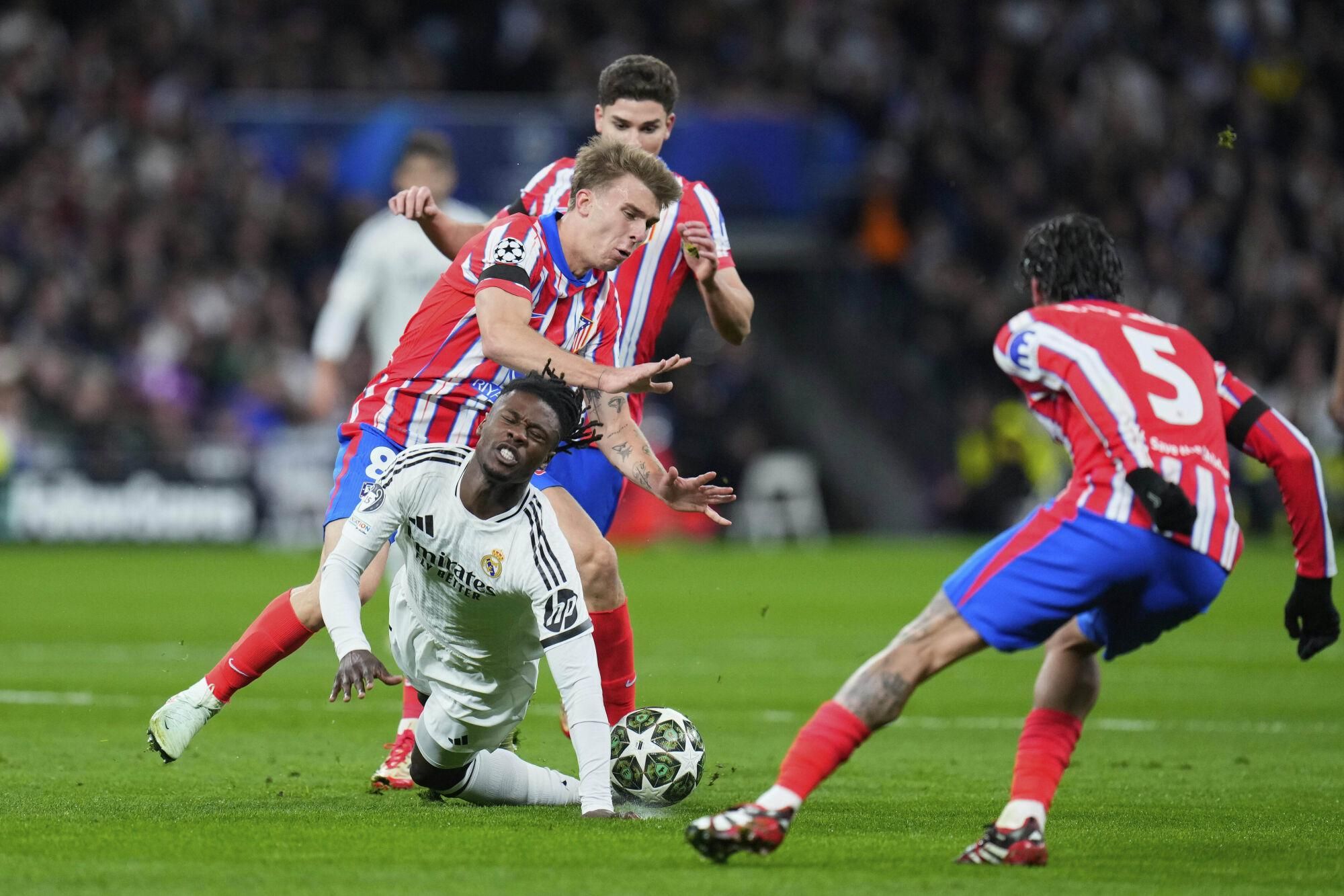 Real Madrid's Eduardo Camavinga, bottom left, is challenged by Atletico Madrid's Pablo Barrios, left, and Atletico Madrid's Rodrigo De Paul, right, during the Champions League round of 16 first leg soccer match between Real Madrid and Atletico Madrid at the Bernebeu stadium in Madrid, Spain, Tuesday, March 4, 2025. (AP Photo/Manu Fernandez). EDITORIAL USE ONLY / ONLY ITALY AND SPAIN