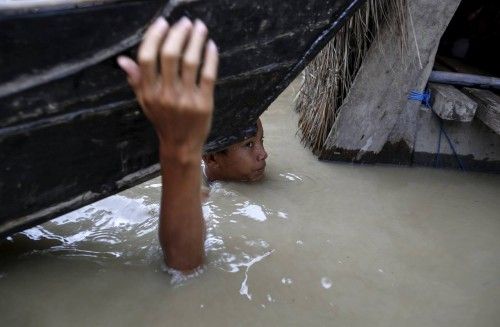 A boy moves his boat in a flooded village outside Zalun Township, Irrawaddy Delta,
