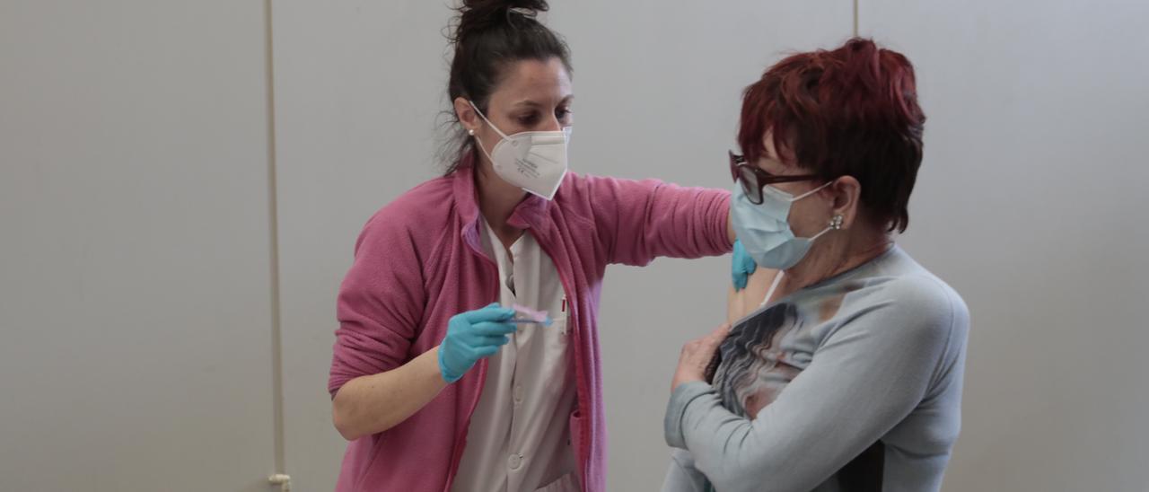 Una enfermera vacuna a una mujer en Gijón.