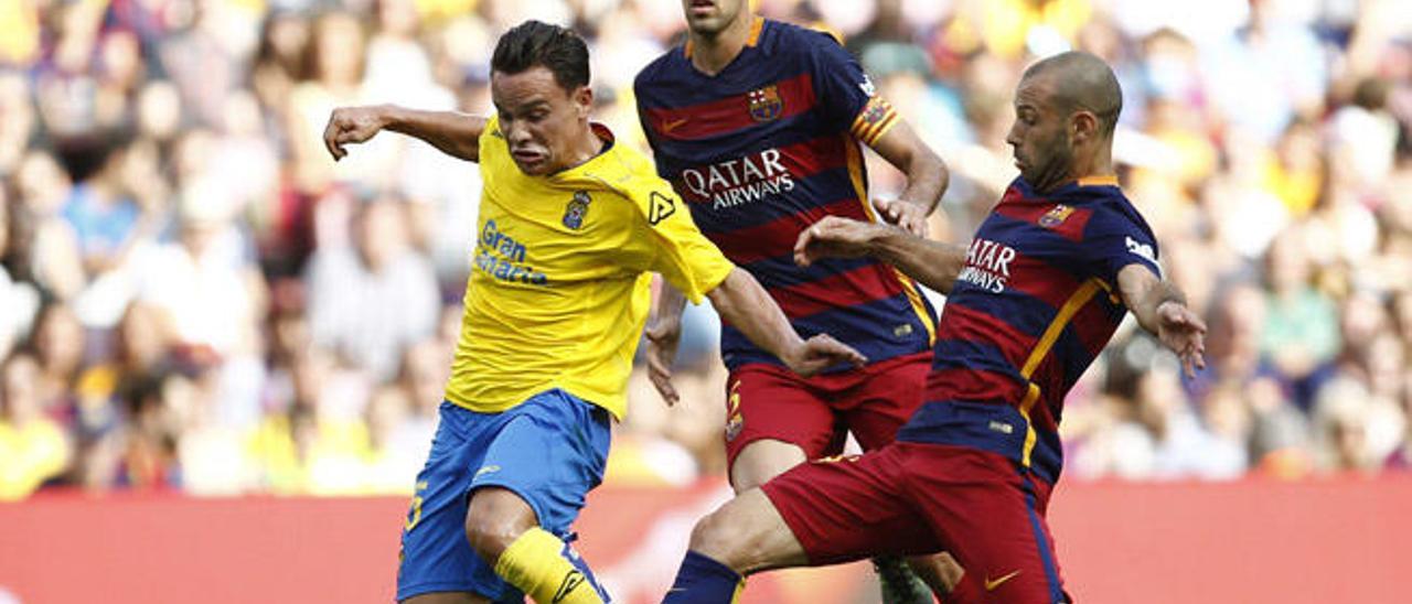 Roque Mesa conduce el balón ante la defensa de Mascherano y Busquets, en segundo término.