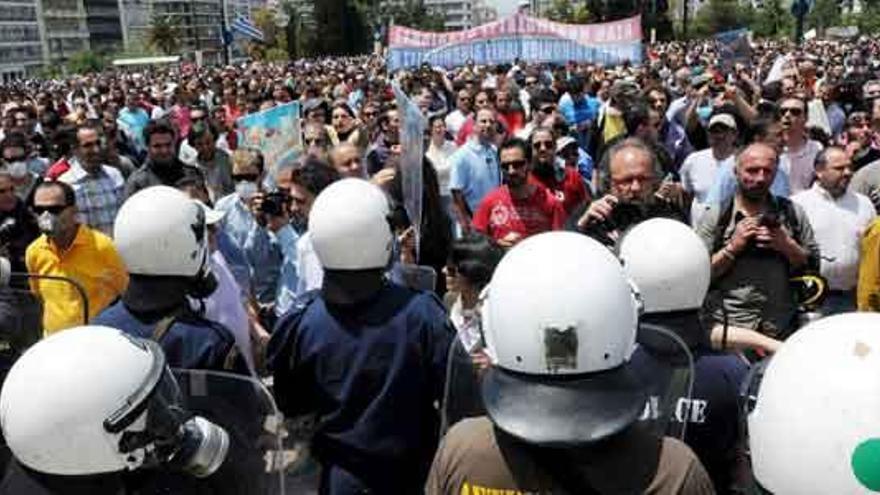 Policías antidisturbios vigilan a los griegos que se manifiestan.
