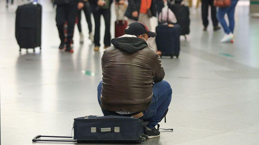 Un viajero sentado sobre una maleta en la estación de Atocha.