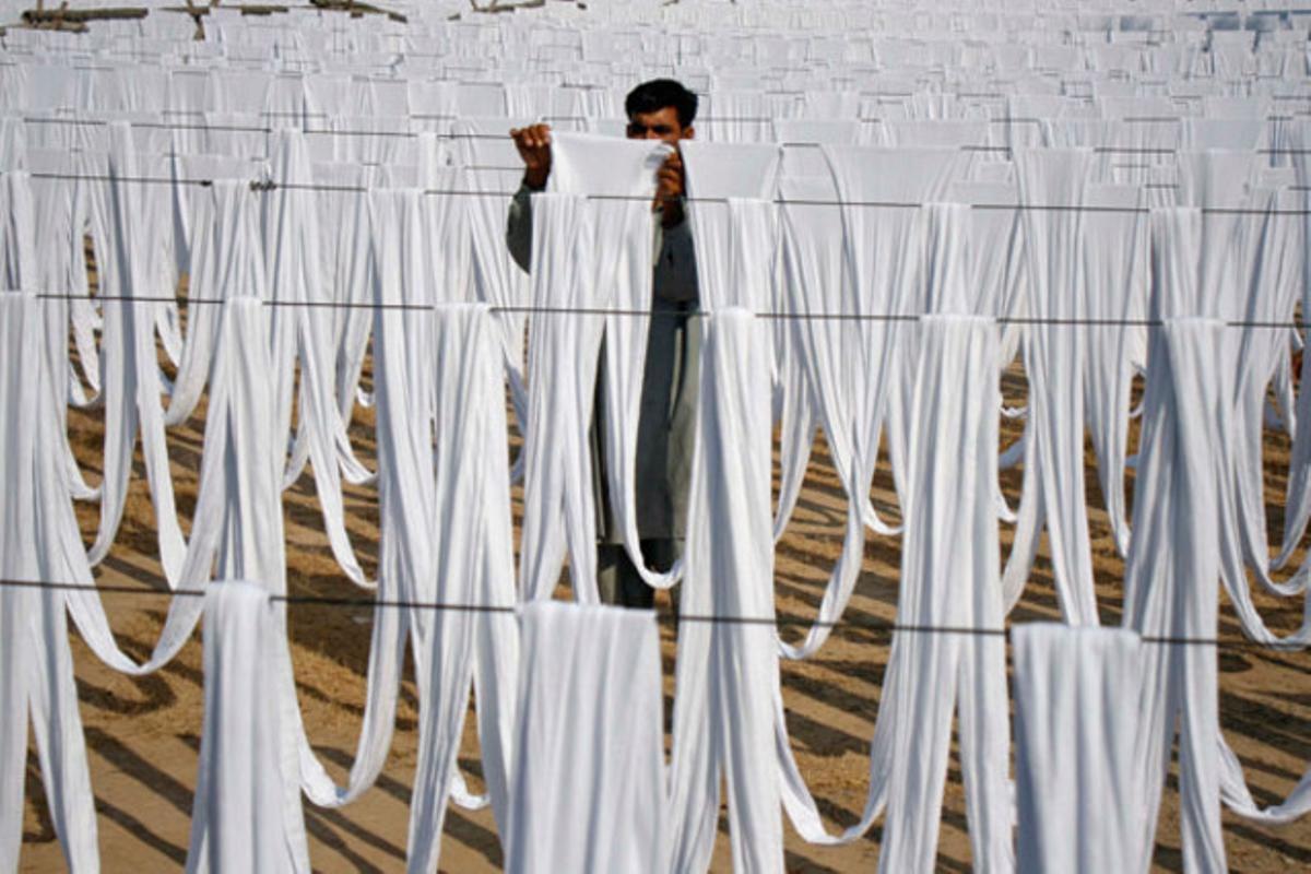 Un home estén els llençols al sol en un camp a Faisalabad (Pakistan).