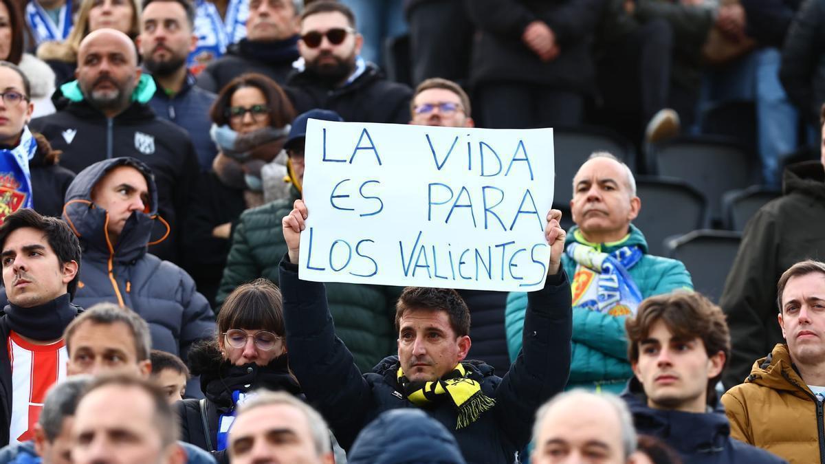 Un aficionado sujeta una pancarta con el lema "la vida es para los valientes".