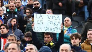 Un aficionado sujeta una pancarta con el lema la vida es para los valientes.