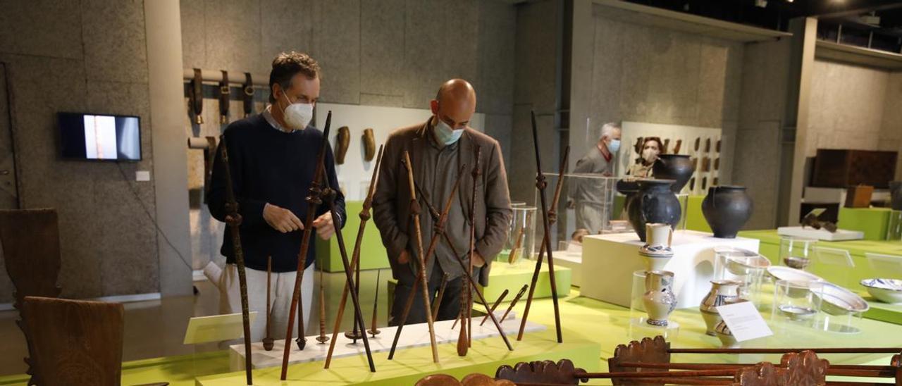 Xuacu López, director del Muséu del Pueblu d&#039;Asturies y Miguel Barredo, director de la Fundación Municipal de Cultura, en la exposición, delante de las cerámicas y otros objetos cotidianos.