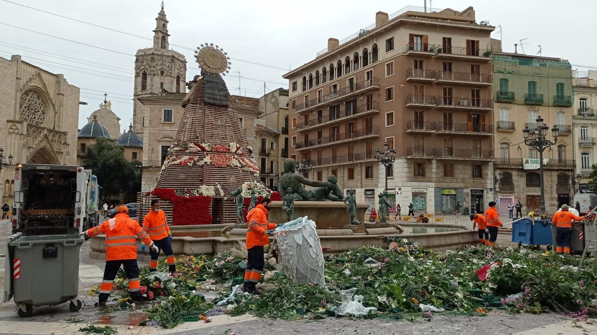 Operarios de la limpieza retiran las flores de la plaza de la Virgen.