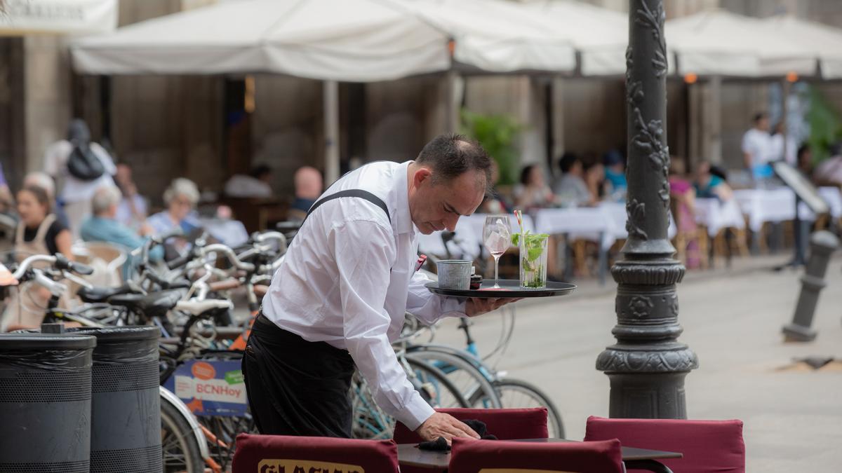 Un camarero arregla una mesa en una terraza.