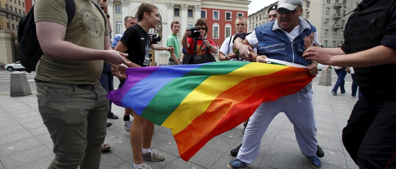 Un hombre intenta retirar la bandera LGTBI a un grupo de manifestantes en favor de los derechos de la comunidad, en el centro de Moscú en mayo de 2015.