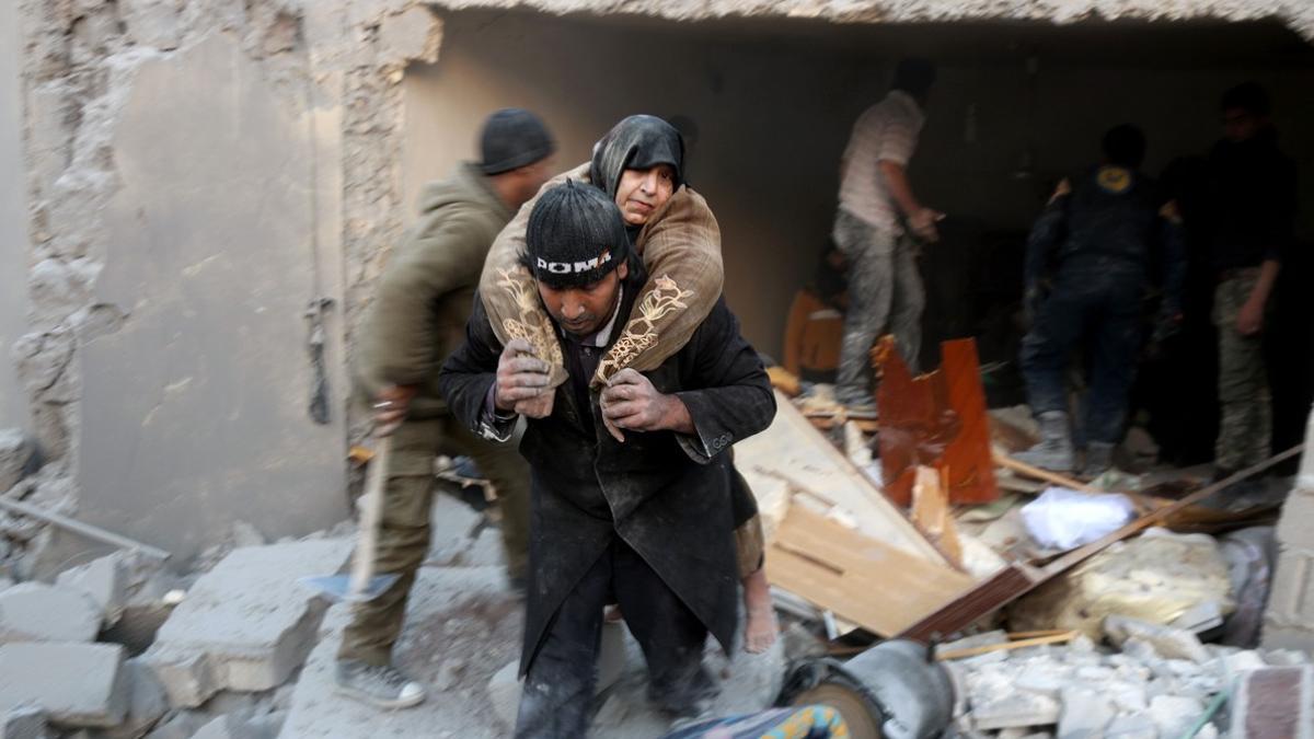 Un socorrista pone a salvo a una mujer tras deplomarse el edificio donde vivía por un bombardeo.