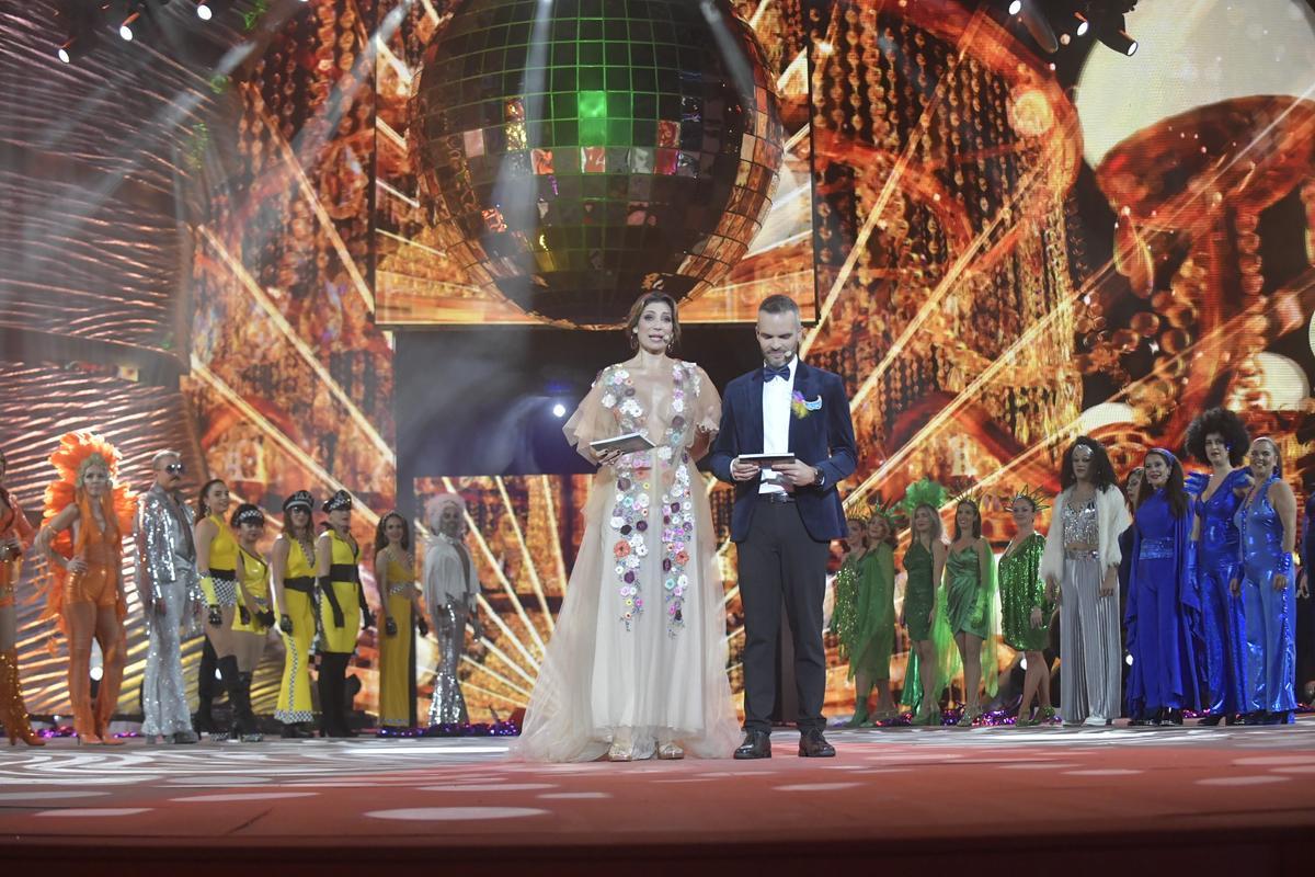 Los presentadores de la gala Emilia González y David Perdomo junto a Danza Las Palmas, ganadores del primer premio de disfraces adultos en la categoría de grupos.