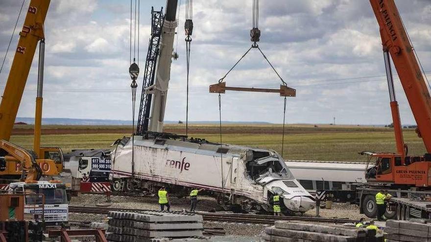 Tres grandes grúas se coordinan para lograr levantar la locomotora más dañada por el accidente, que se examinará en Madrid.