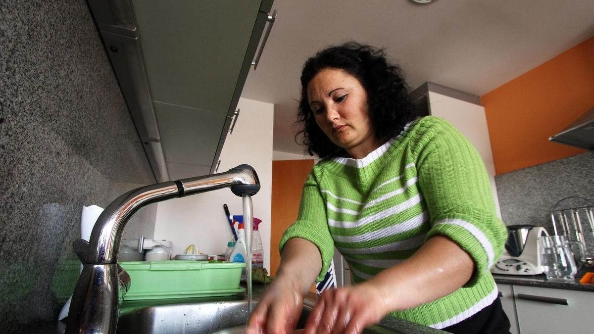 Una trabajadora del hogar friega los platos en un domicilio durante su jornada laboral.